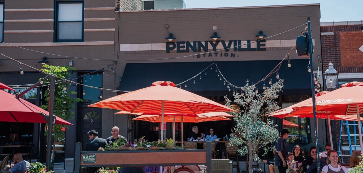 Pennyville Station restaurant patio in Park Ridge, Illinois, with outdoor dining under orange umbrellas